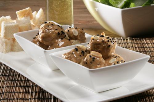 Albondigas met gehakte amandelen en zwarte olijven in truffelsaus.
